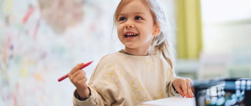 Nursery child holding a pen