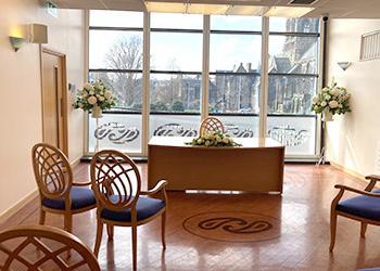 A photo of the wedding suite showing the couple's chairs at the front left of the registrar's desk and another chair on the right.