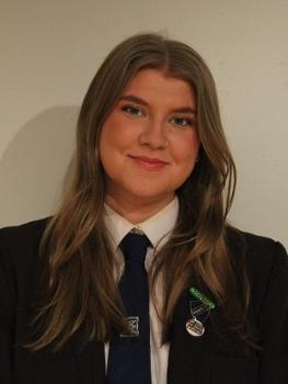 Head and shoulders shot of young woman with long hair smiling to camera