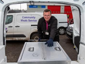 View from inside a van with back doors open at a man placing large box inside