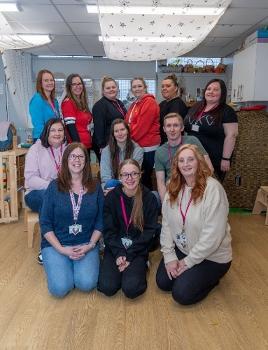 Posed group image of nursery staff smiling to camera