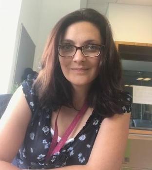 Selfie image of a woman with medium length brown hair and glasses