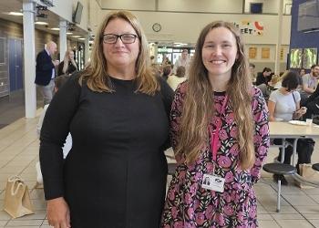 Two women stand side-by-side smiling to camera