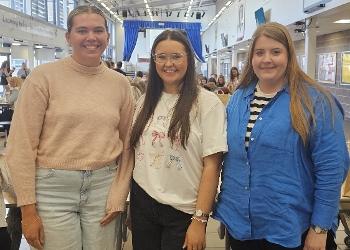 Three women stand side by side smiling to camera