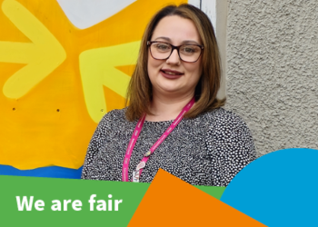A dark-haired woman stands in front of a colourful wall smiling to the camera. Text reads 'We are fair'
