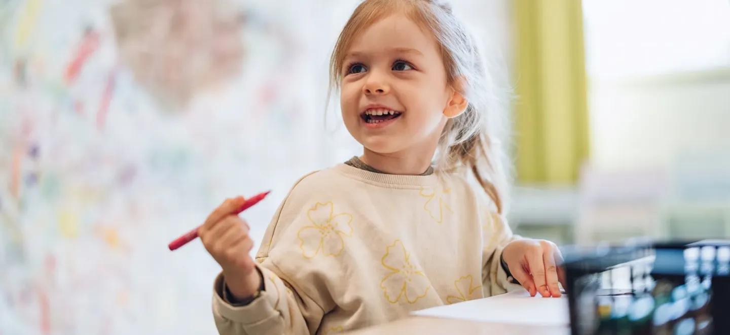 Nursery child holding a pen