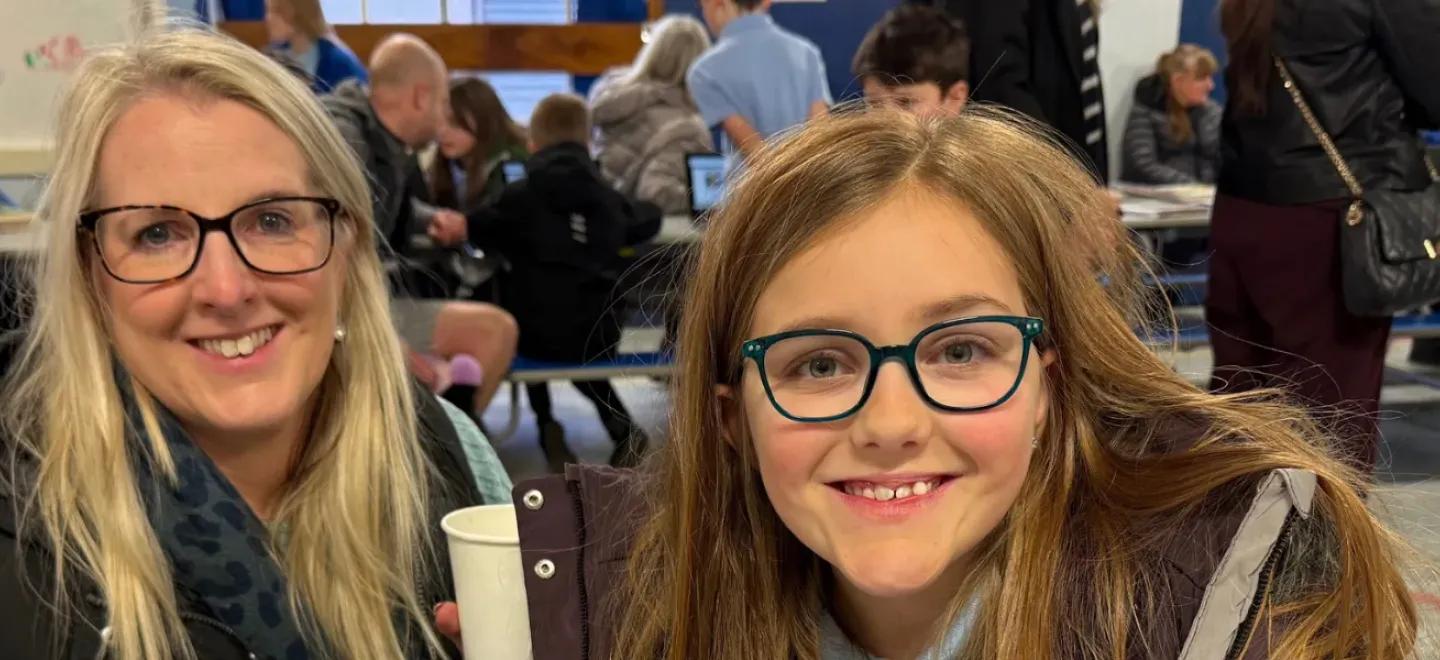 A parent and child smile at a school event.