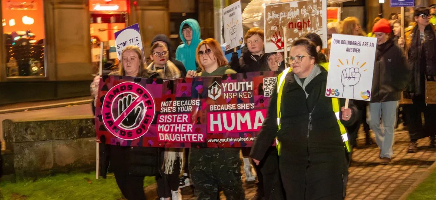 People walking with banners on a Paisley street.