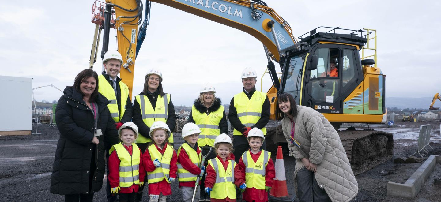 Construction workers and young children pictured on the site of the new Thistle Primary