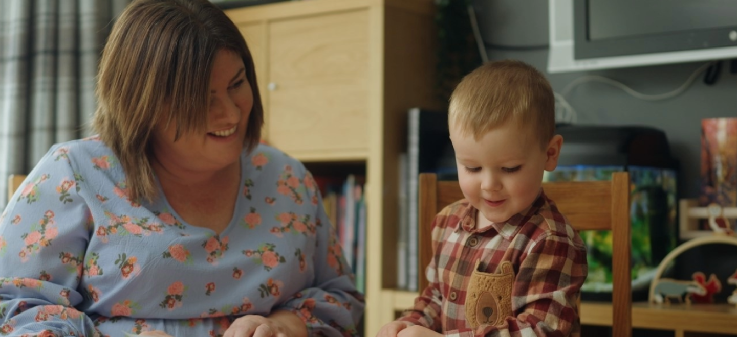 Childminder and child reading in a home environment.