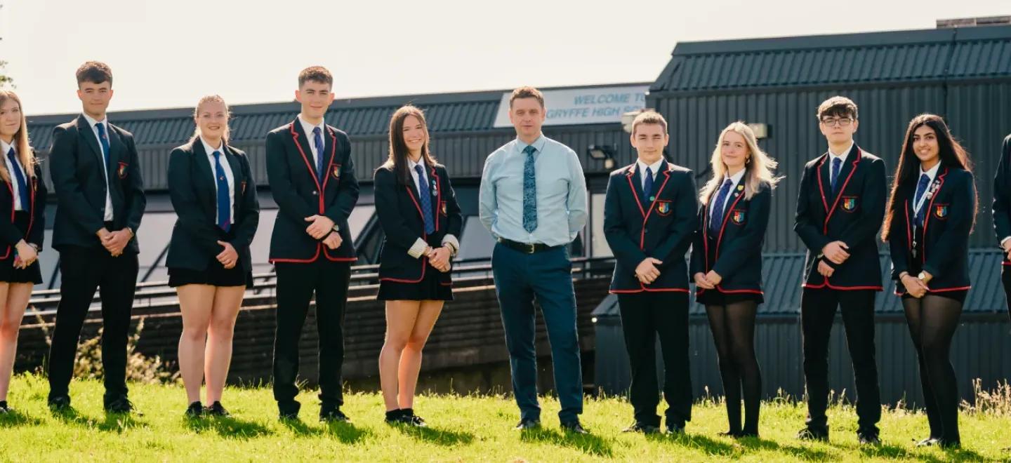 A group of senior high school pupils on the grass outside their school with Head Teacher Kevin Christie.