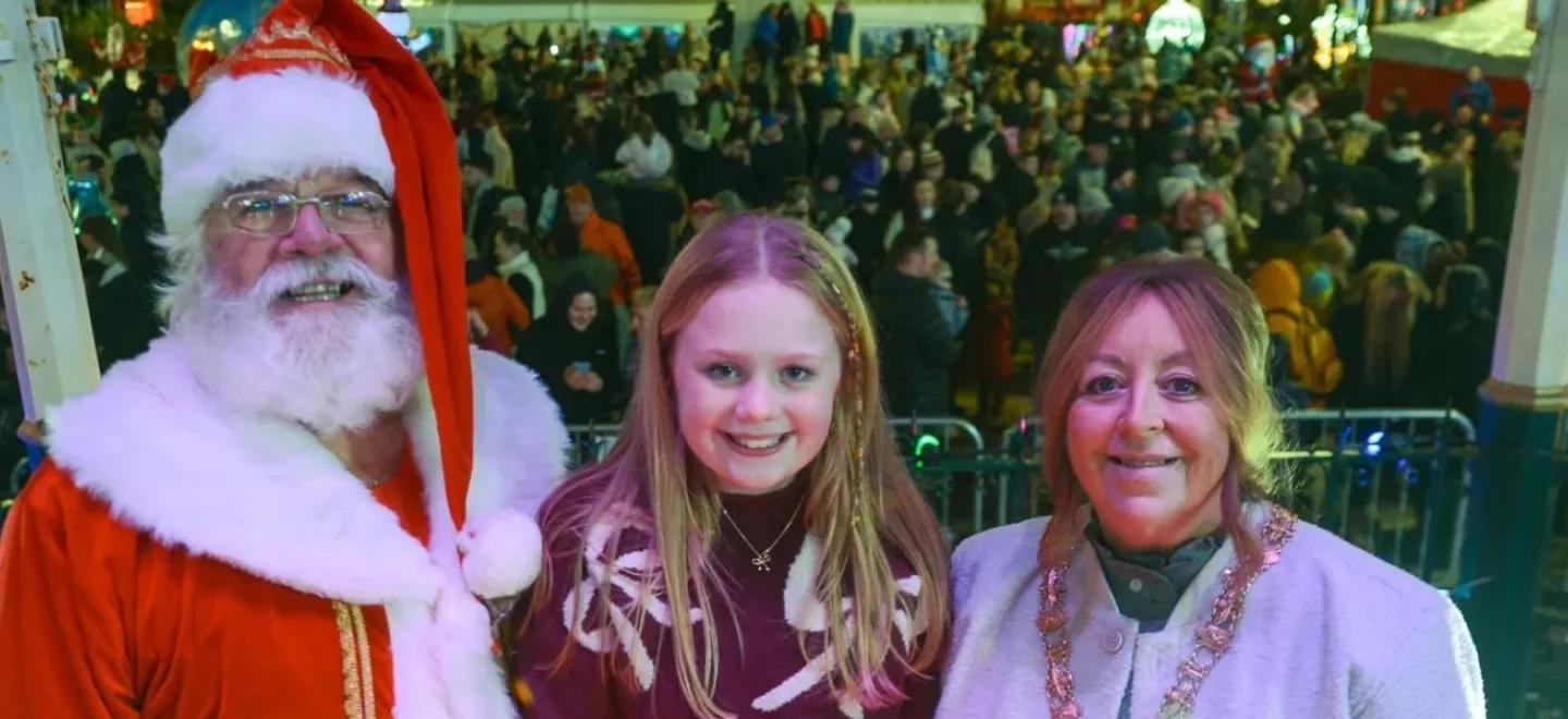 Santa with a primary school aged child and Provost of Renfrewshire on stage to switch on Christmas lights.